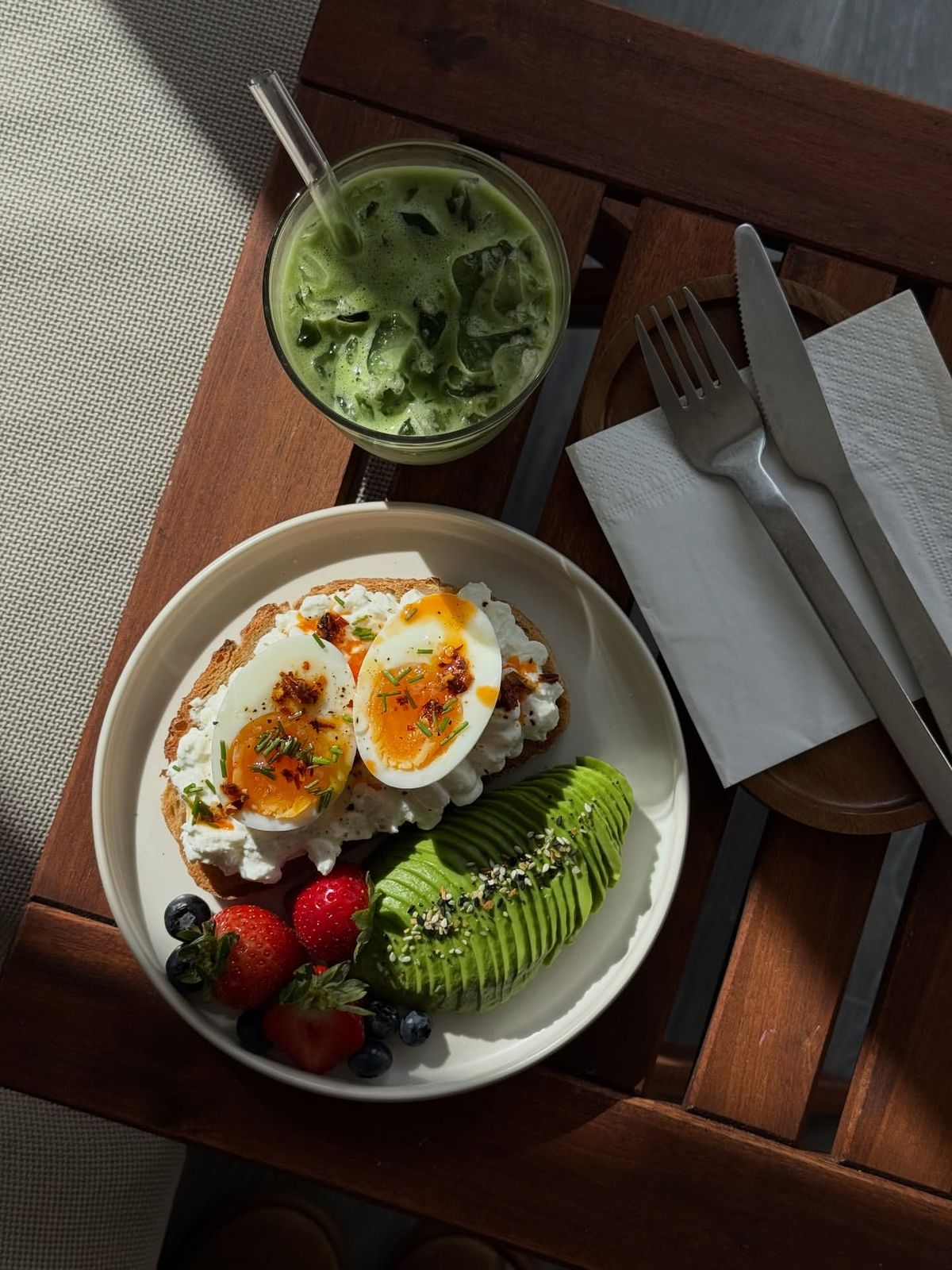 A balanced breakfast plate with eggs, avocado, fruit and a matcha